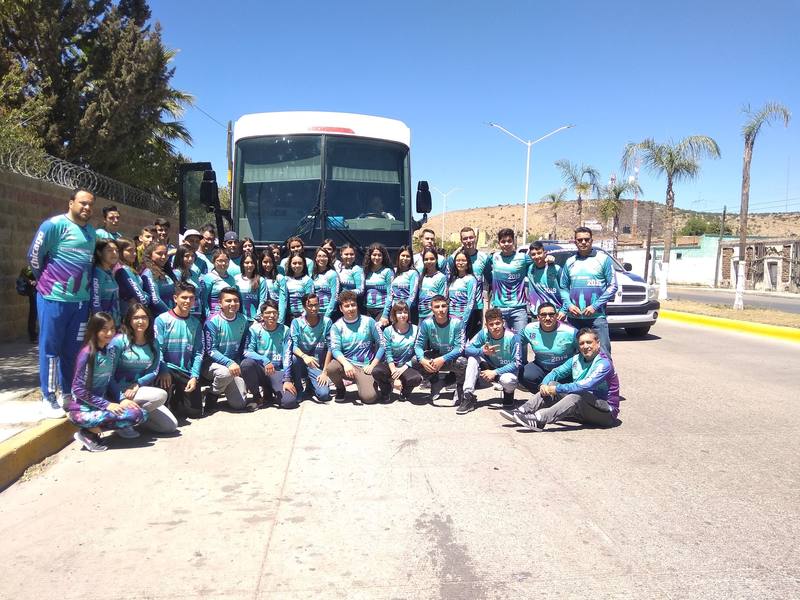 About forty students and teachers in matching teal Student Exchange 2019 jerseys in front of a coach bus in Durango